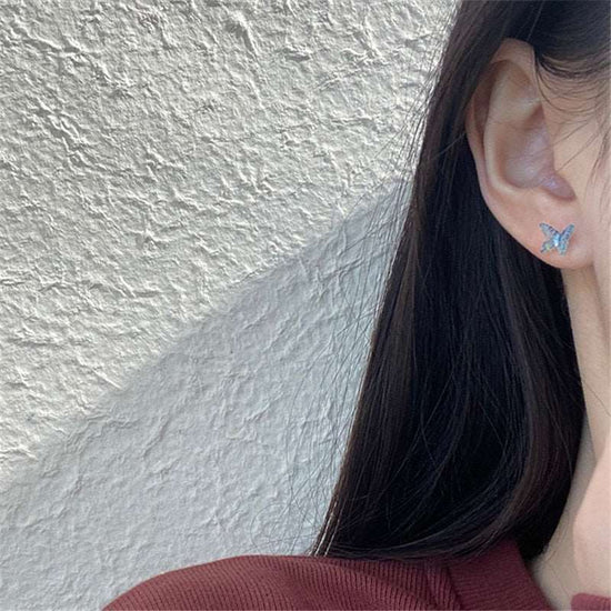 Dreamlit Butterfly Stud Earrings in Greenish Blue worn with hair tucked behind the ear.