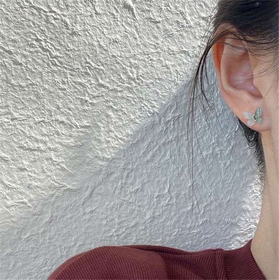 Close-up of sea green Dreamlit Butterfly Stud Earrings being worn.