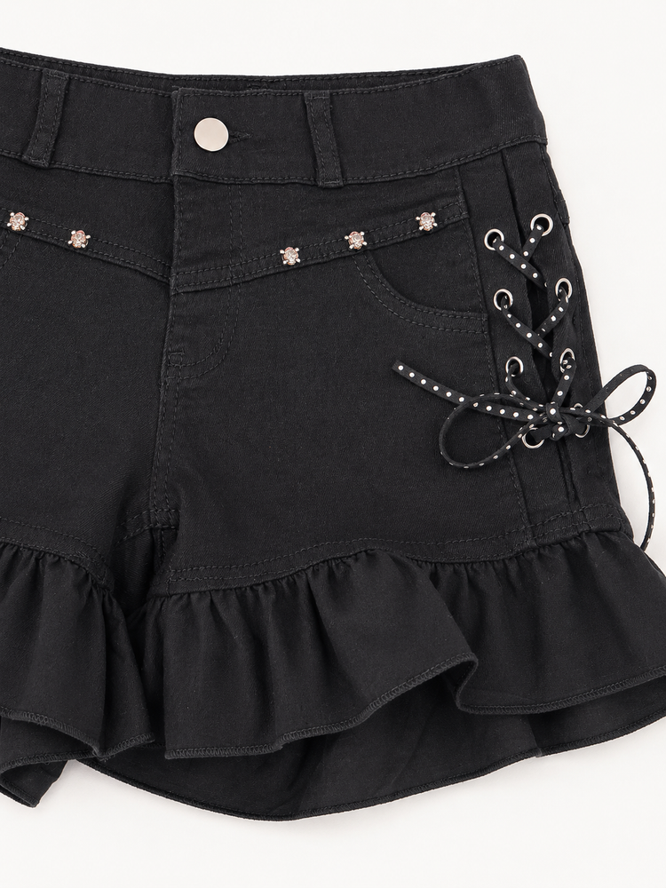 Close-up of Two Moody Originals: Pretty Dangerous Shorts showing skull embellishments, studded ribbon lacing, and ruffle trim details.