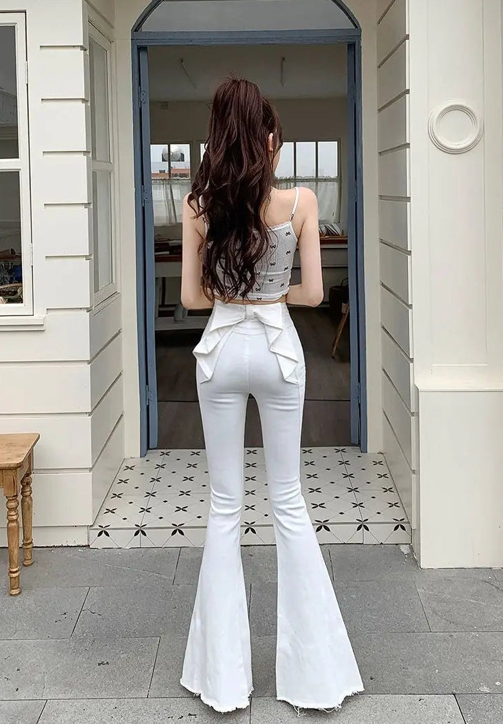 Outdoor photo of a model in the white Backstage Bow Flare Jeans with soft natural lighting.