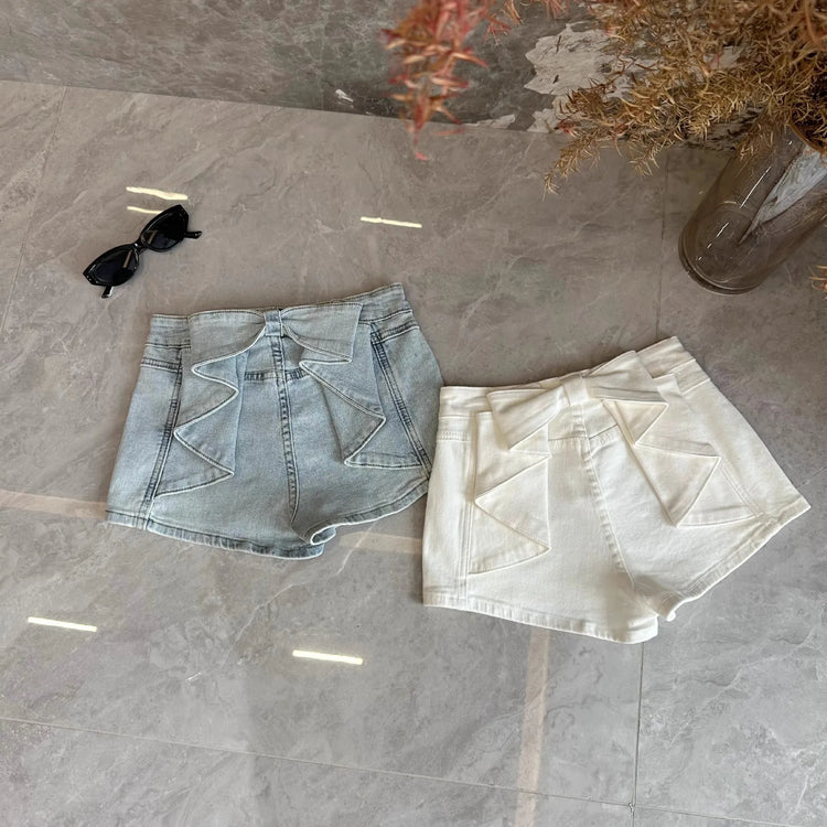Overhead flat lay of the Backstage Bow Shorts in white and light blue.