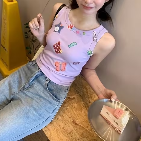 Seated model wearing the light lavender Charm Collector Tank with light-wash jeans beside a dessert plate.