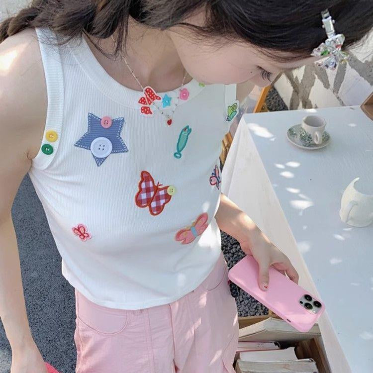Overhead view of a model wearing the white Charm Collector Tank with pink shorts and accessories.