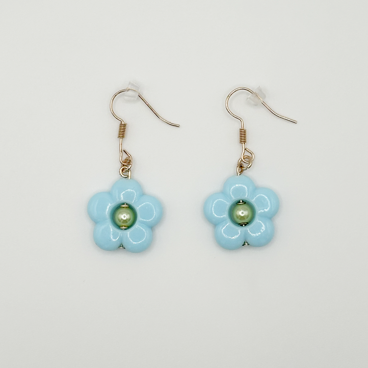 The Daisy Sky Earrings featuring soft blue daisy charms with a glossy finish in a lightweight, dreamy design.