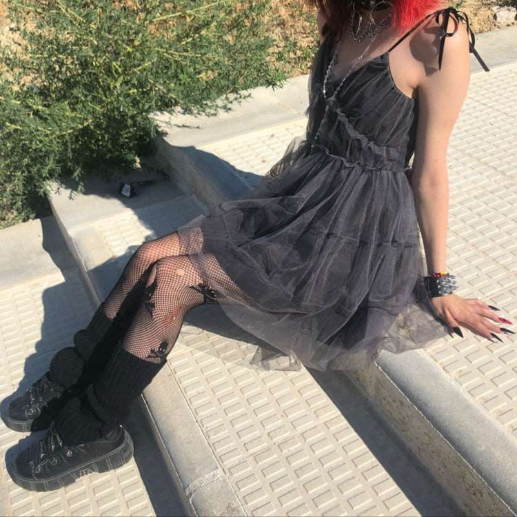 Seated side outdoor view of model wearing the Dark Fairy Tulle Dress showing layered skirt and tie straps