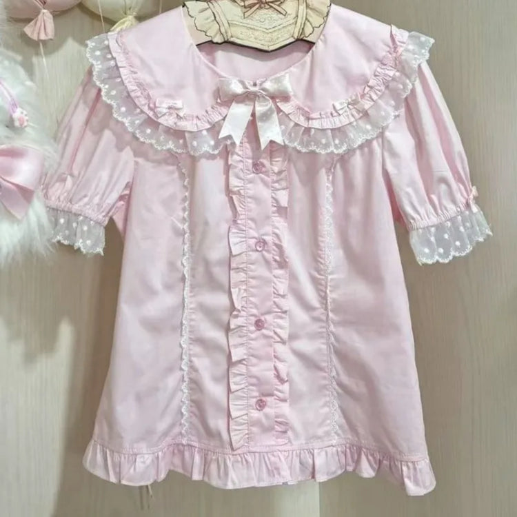 The Darling Honey Bear Blouse in pink on a hanger, showcasing bow and lace details.