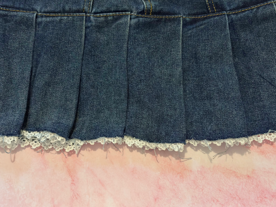 Close-up of lace trim along the front hem of the Denim Daydream Pleated Lace Skort