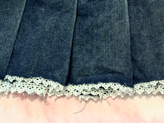 Extreme close-up of lace trim detailing on the Denim Daydream Pleated Lace Skort