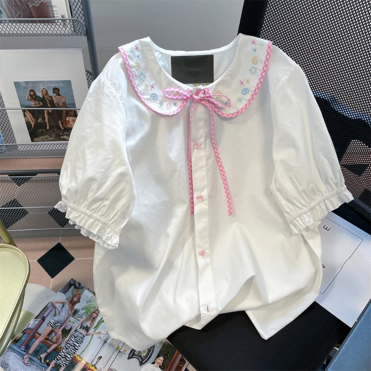 Front flat lay of the Doodle Darling Collar Blouse in white with pastel embroidered collar, pink gingham trim, and puff sleeves