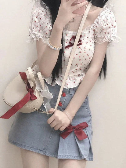 A close-up of the Dual Darling Denim Skirt's pleated side, styled with a ribbon-adorned bag for a sweet look
