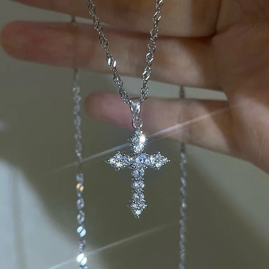 Close-up of the Eternal Shine Cross Necklace in silver with crystal accents, held by hand.