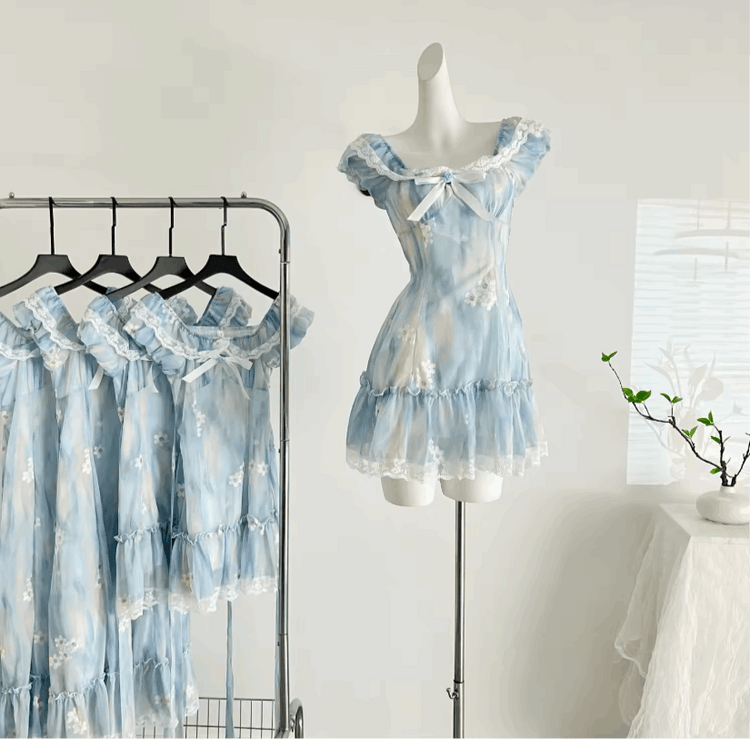 The mini Ethereal Flower Princess Dress on a mannequin next to a rack with the mini and midi versions of the dress hanging on it.