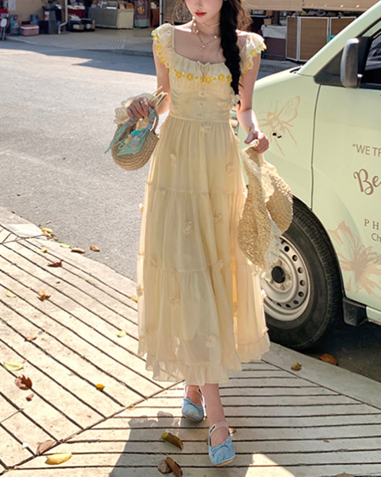 Model wearing the Ethereal Flower Princess Heavenly Bloom Midi Dress in light yellow outdoors with daisy-trimmed neckline and 3D floral appliqués.
