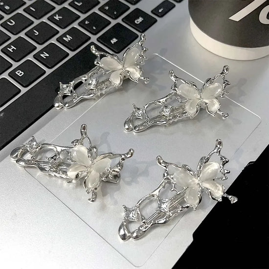 Four silver Liquid Metal Butterfly Hair Clips resting on a laptop keyboard.