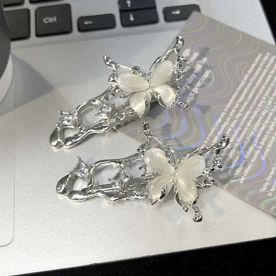 Two silver Liquid Metal Butterfly Hair Clips resting on a laptop keyboard.