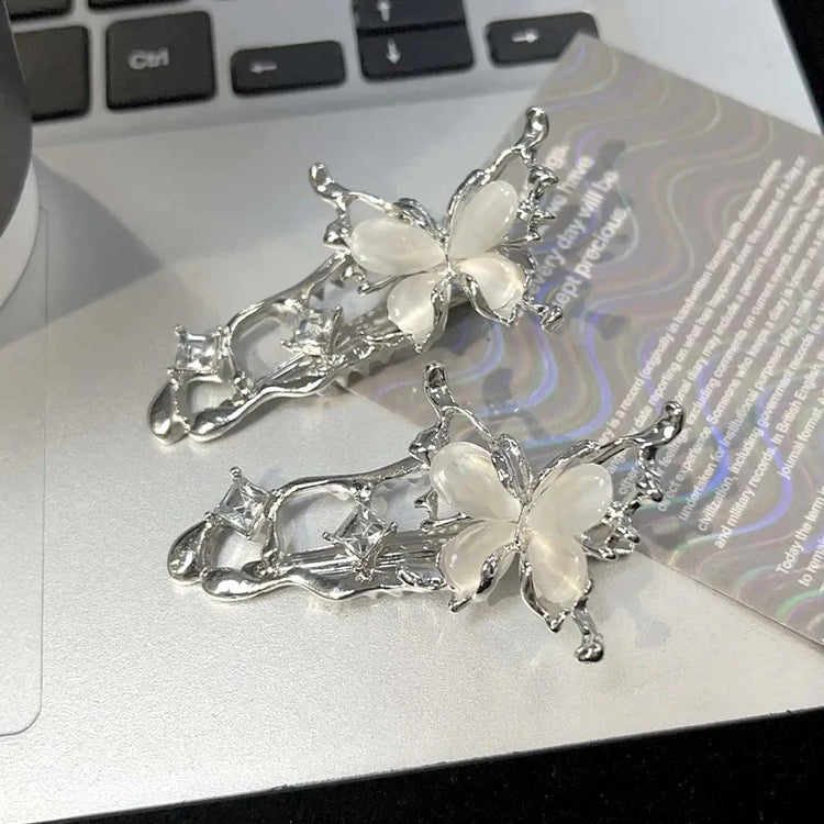 Two silver Liquid Metal Butterfly Hair Clips resting on a laptop keyboard.