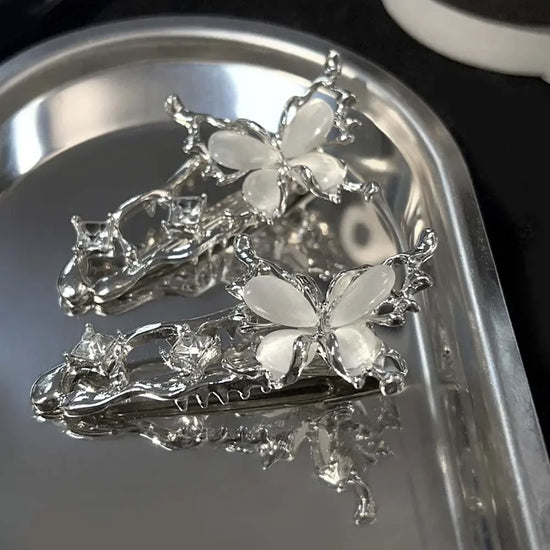 Two Liquid Metal Butterfly Hair Clips displayed on a reflective silver tray.