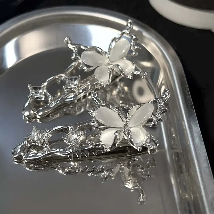 Two Liquid Metal Butterfly Hair Clips displayed on a reflective silver tray.