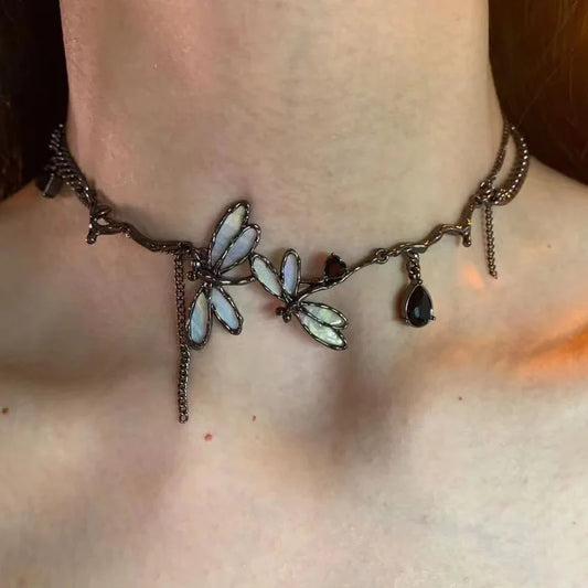 The Moonvine Dragonfly Necklace styled in warm moody lighting, highlighting the elegant dragonfly centerpiece and dark gemstone accents.