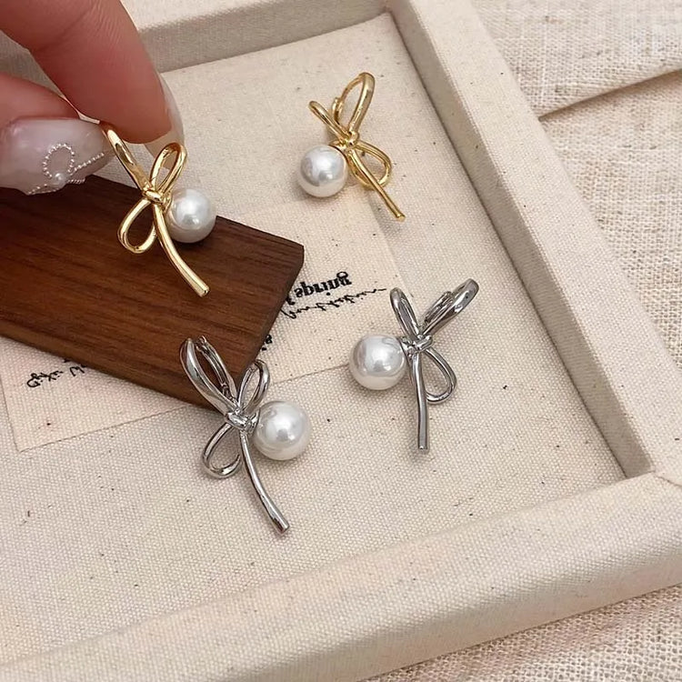 Gold and Silver Pearl Whim Bow Earrings displayed together in a box