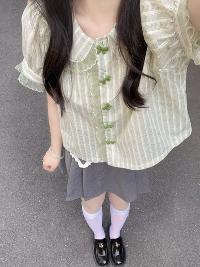 Model styling Pistachio Ribbon Striped Blouse with a gray pleated skirt and loafers