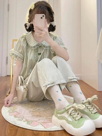 Seated view of Pistachio Ribbon Striped Blouse paired with socks and green sneakers