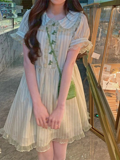 Model wearing mini-length Pistachio Ribbon Striped Dress in front of a bakery case.