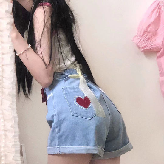 Back view captures the heart patch design and classic light wash denim on the Scarlet Sweetheart High-Rise Shorts