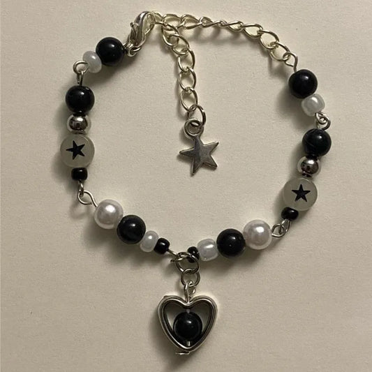 Close-up of the black Set Apart Star Bracelet with black heart charm and metallic accents on a light background