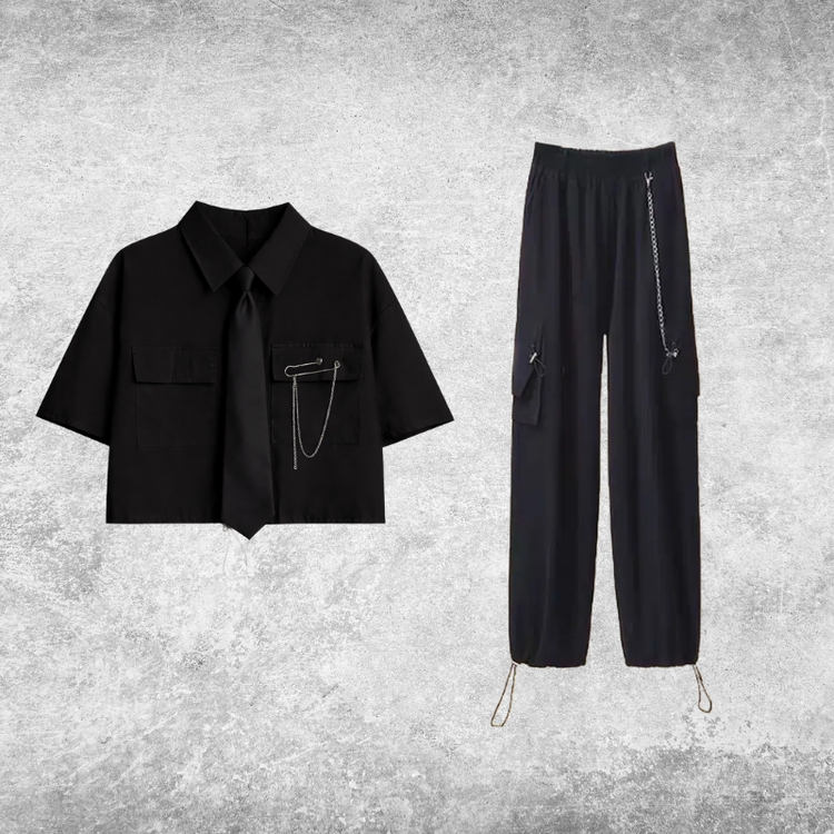 Black short-sleeve cropped button-up shirt from the Shadow Chain Utility Set featuring a matching black tie, removable safety pin with chain, and adjustable drawstring waist, paired with black utility pants featuring a detachable chain and drawstring hems.