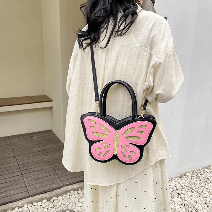 Sparkling Butterfly Handbag in black and pink being worn behind a model's back