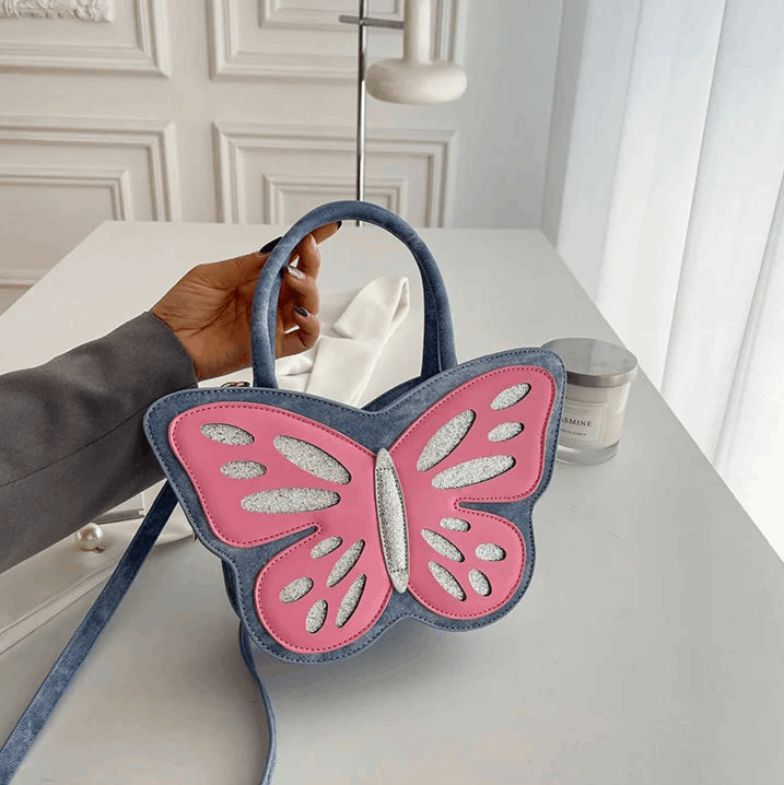 Model holding blue and pink Sparkling Butterfly Handbag up on a table