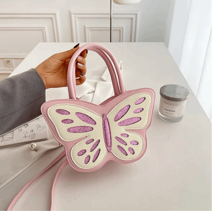 Model holding the Sparkling Butterfly Handbag in pink and white on a table