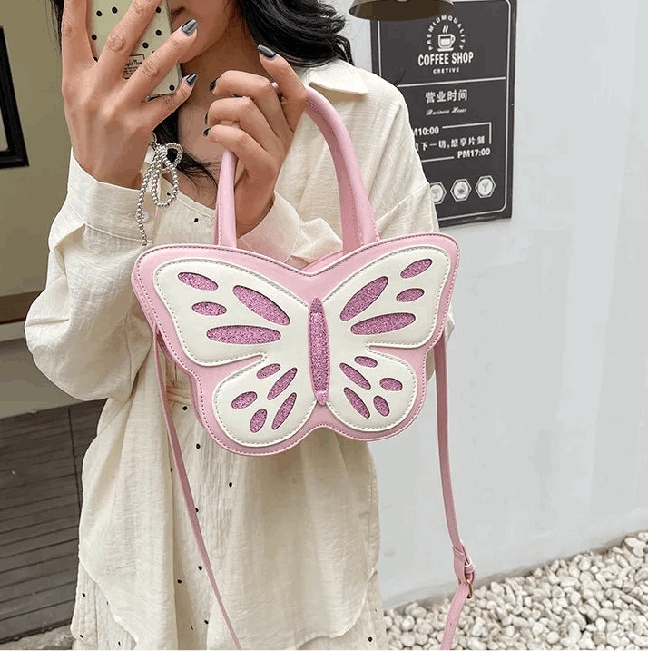Model holding the Sparkling Butterfly Handbag in pink and white up in a mirror