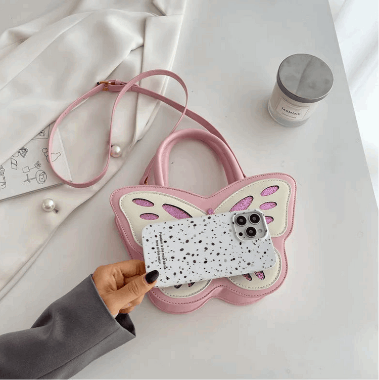Sparkling Butterfly Handbag in pink and white shown with phone for size reference on tabletop