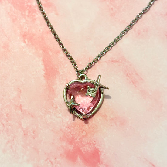 Detailed. close-up of Starlit Love Necklace on pink marbled background