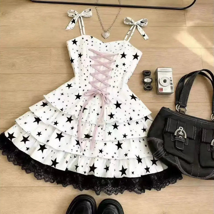 Close-up of the Starry-Eyed Fantasy Dress bodice showing the black star print on structured white fabric, pink corset-style lace-up front, and black lace trim