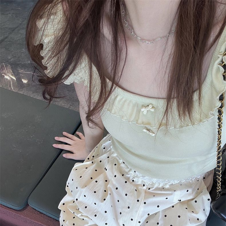 Close overhead view of the Sweet Clover Ruffle Top showing its ribbed texture, ruffled scoop neckline, and small bow accents.