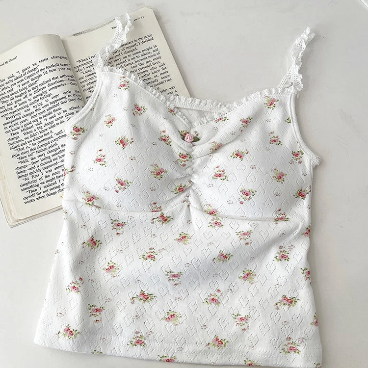 White/red floral Sweet Flower Crop Top laid flat next to an open book, featuring lace trim and ruched bust.