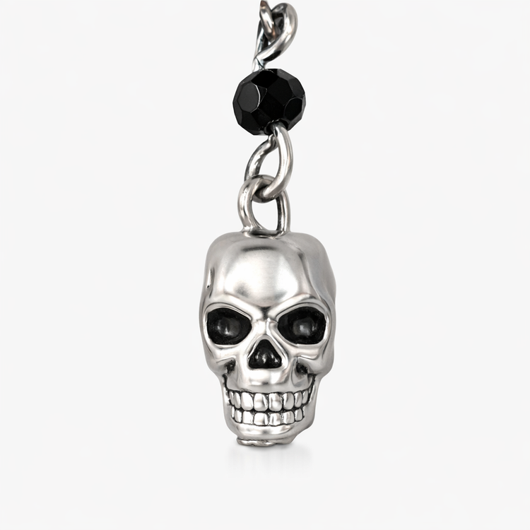 Close-up detail of Til Death Do We Sparkle Earrings silver-plated skull charm, showing black bead accent and polished finish.
