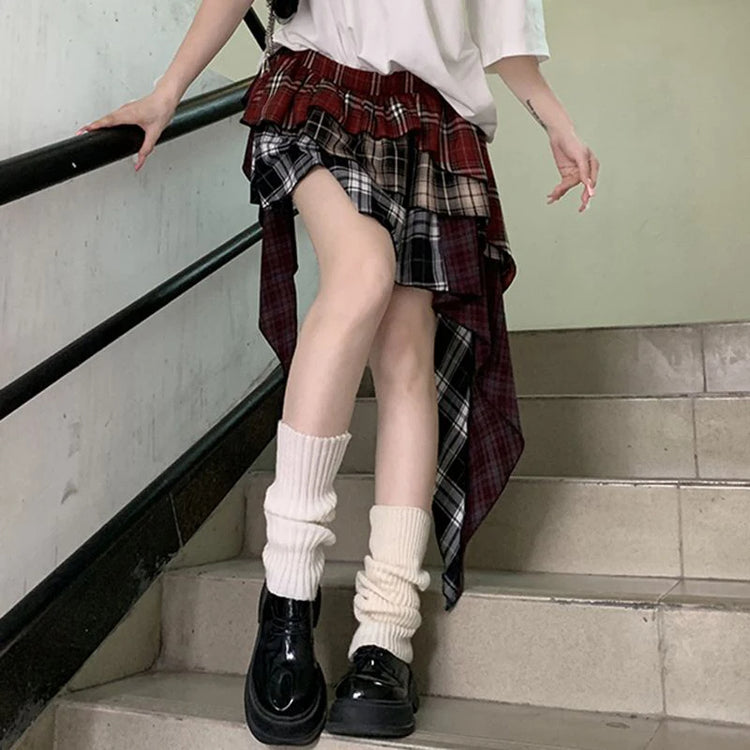 Model wearing the Tilted Temper Tartan Skirt standing at a slight angle with one knee bent, showing asymmetrical layers and design