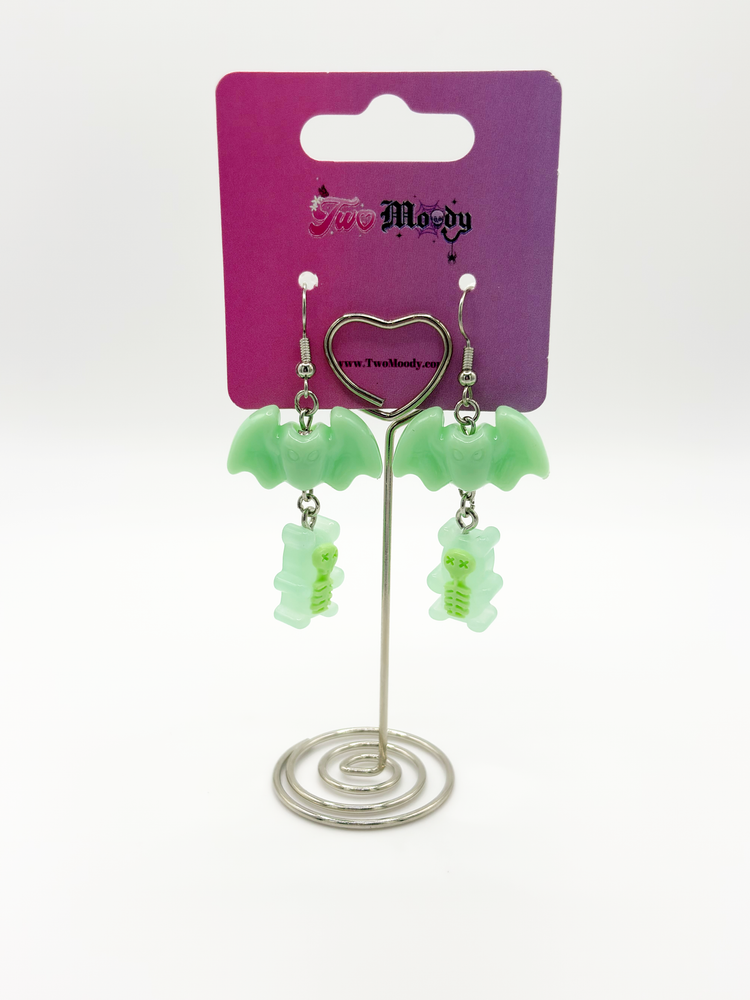 Two Moody Originals Candy Bite Bat Earrings mint version displayed on stand