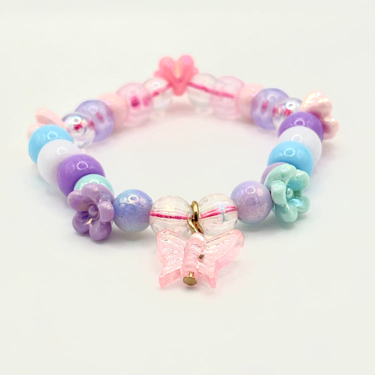 Another angle of the Two Moody Originals: Kandi Bracelet in Daydream Wings, with a focus on the dangling butterfly charm, flower charms, and beading