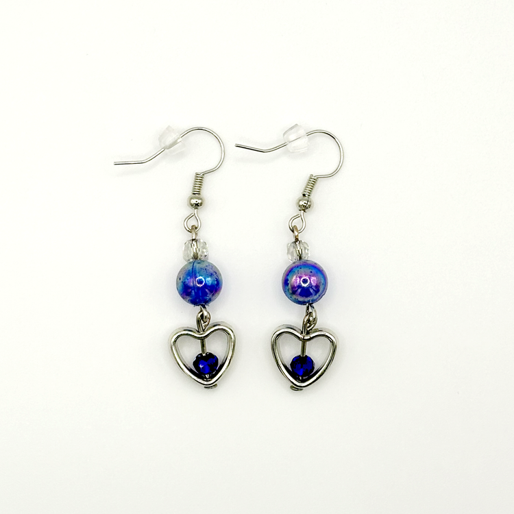 Two Moody Originals: Lovestruck Charm Earrings with iridescent blue beads, clear crystal accents, silver heart charms, and deep blue crystal centers.