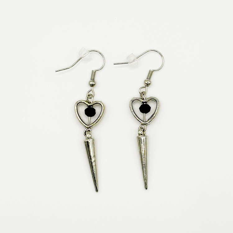 Two Moody Originals: Pierced Heart Dagger Earrings with silver open heart charms, black crystal accents, and dangling silver dagger details.