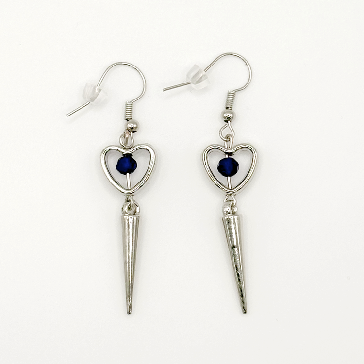 Two Moody Originals: Pierced Heart Dagger Earrings with silver open heart charms, blue crystal accents, and dangling silver dagger details.