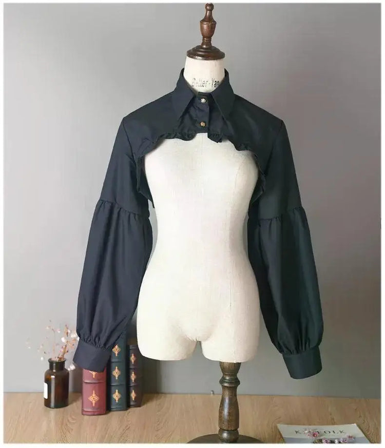 Front view of the black Ultra Cropped Layering Blouse with the collar buttoned, featuring golden rose buttons, gathered trim, and dramatic long sleeves.