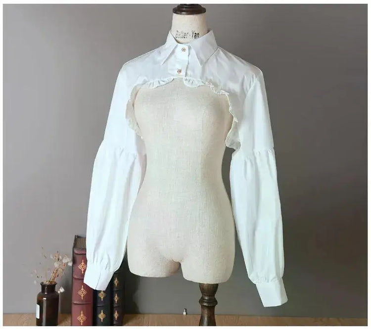 Slightly angled front view of the white Ultra Cropped Layering Blouse with the collar buttoned, featuring golden rose buttons, gathered trim, and dramatic long sleeves.