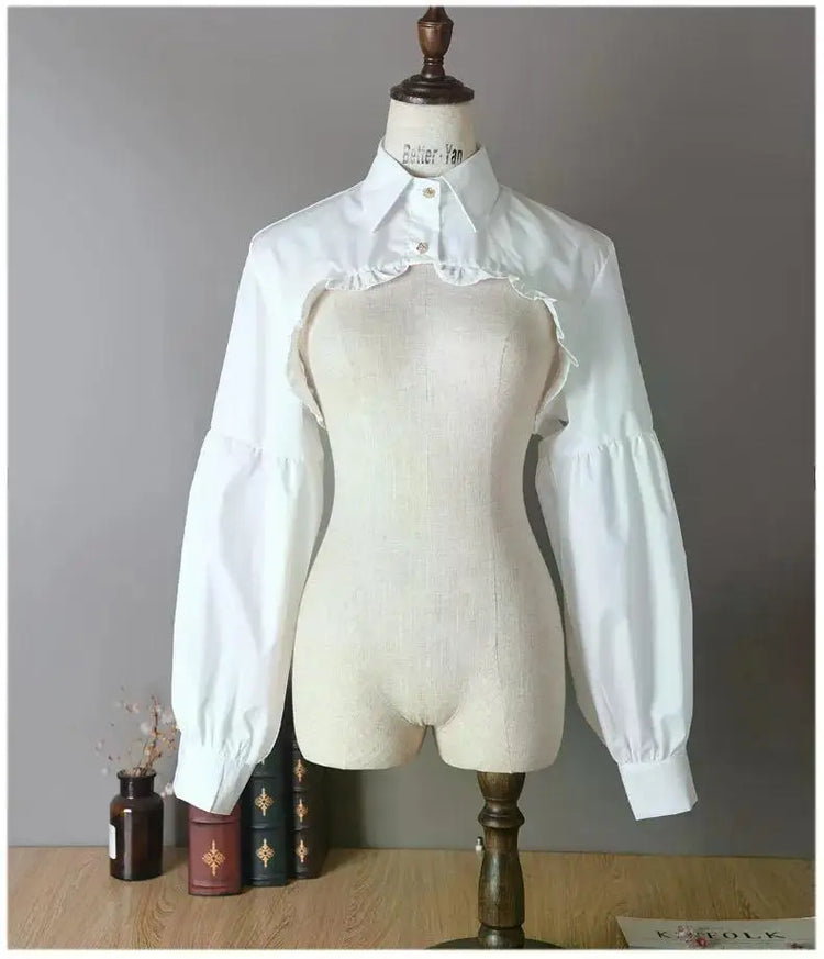 Front view of the white Ultra Cropped Layering Blouse with the collar buttoned, featuring golden rose buttons, gathered trim, and dramatic long sleeves.