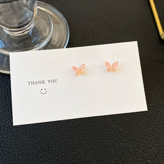 A pair of Dreamlit Butterfly Stud Earrings with a gentle pink and orange ombré.